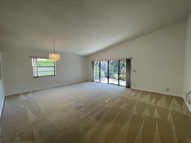 empty room featuring carpet flooring, a textured ceiling, a chandelier, and vaulted ceiling