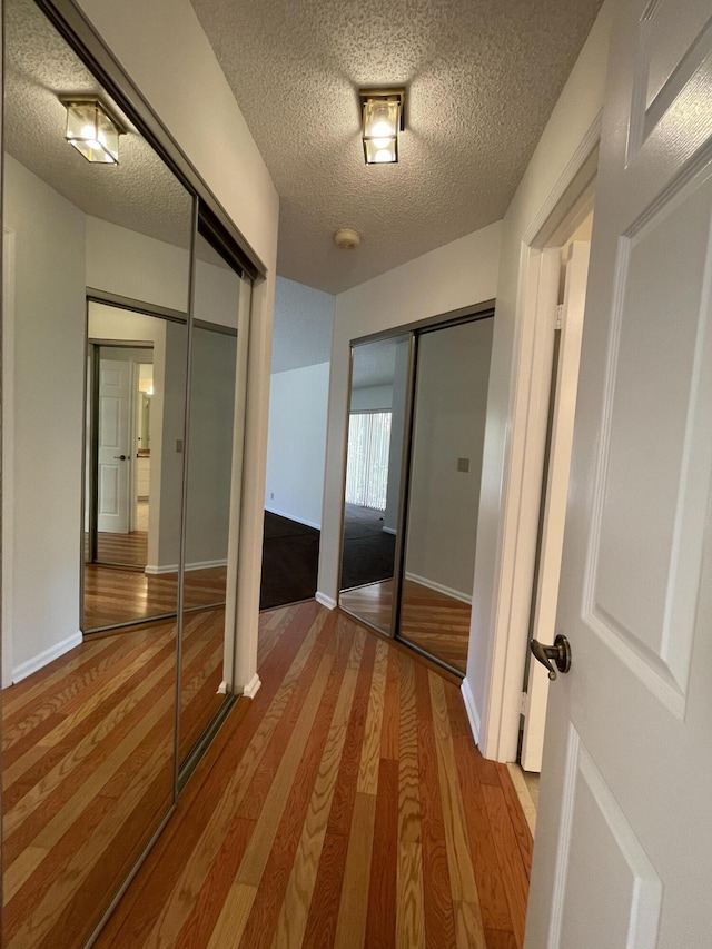 hall with light hardwood / wood-style floors and a textured ceiling