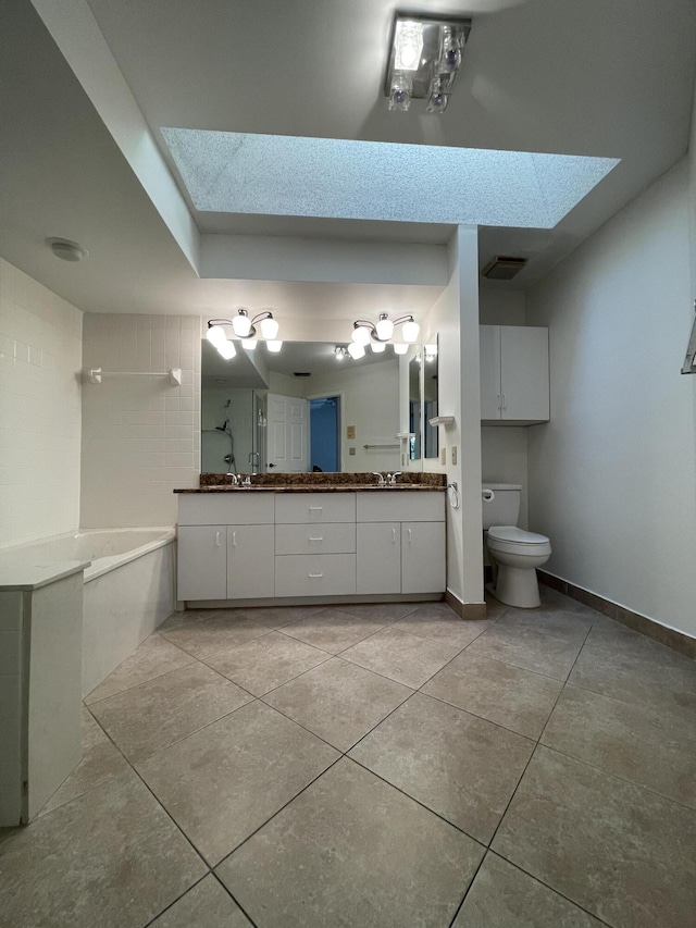 bathroom with a skylight, tile patterned floors, vanity, toilet, and a bathing tub