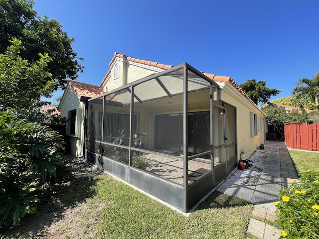 rear view of house with glass enclosure and a yard