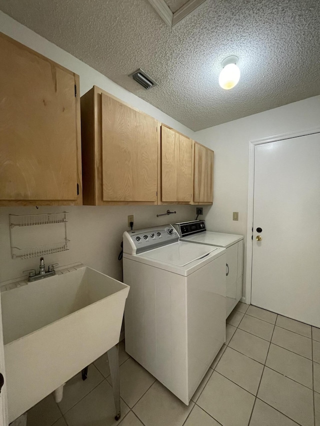 clothes washing area with sink, cabinets, independent washer and dryer, a textured ceiling, and light tile patterned floors