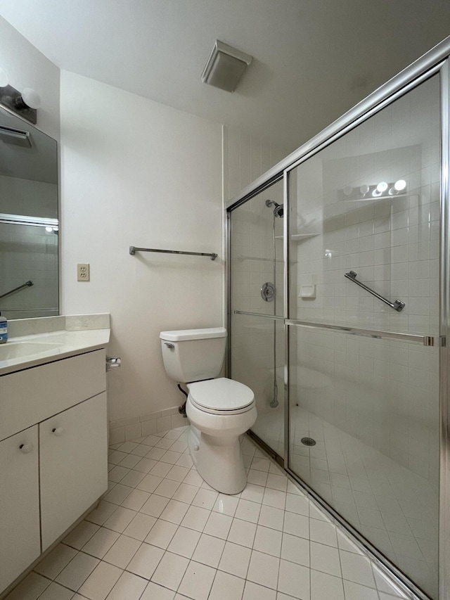 bathroom with toilet, vanity, tile patterned floors, and walk in shower