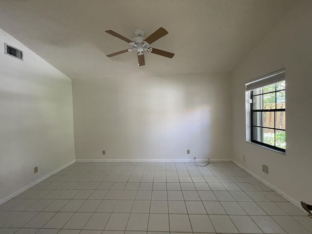 spare room with light tile patterned floors, vaulted ceiling, and ceiling fan