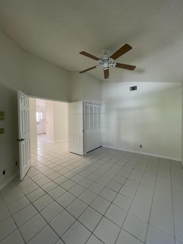 tiled empty room with ceiling fan and lofted ceiling