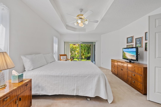 carpeted bedroom with access to exterior, ceiling fan, a raised ceiling, and a textured ceiling