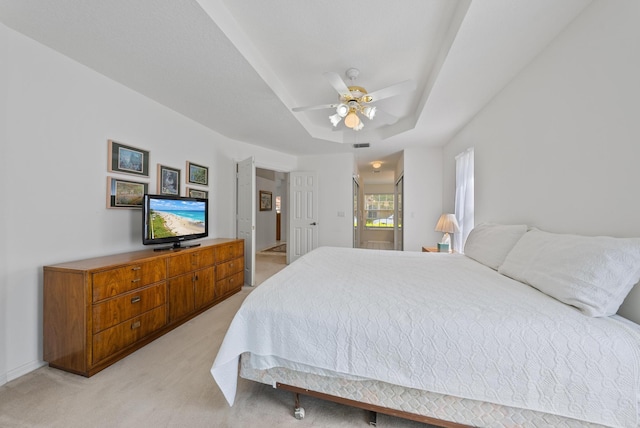 carpeted bedroom featuring a raised ceiling and ceiling fan