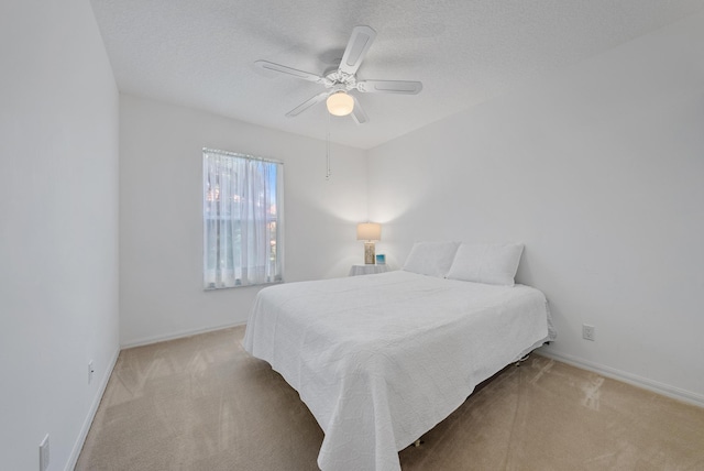 bedroom with a textured ceiling, ceiling fan, and light carpet