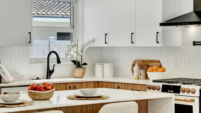 kitchen with backsplash, white cabinets, sink, white gas range oven, and wall chimney exhaust hood