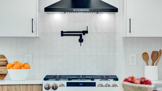 interior details featuring white cabinets, backsplash, stainless steel gas stovetop, and wall chimney exhaust hood