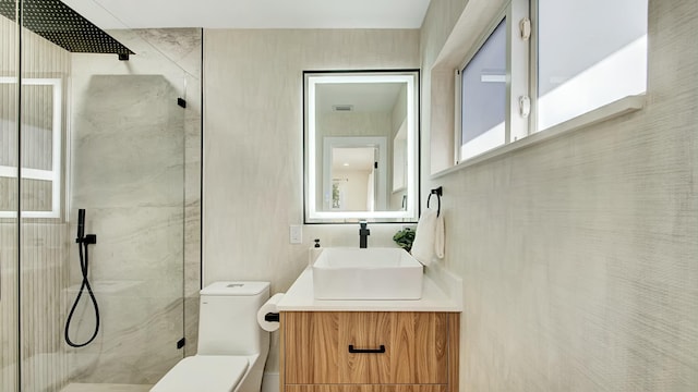 bathroom featuring vanity, toilet, and a shower with shower door