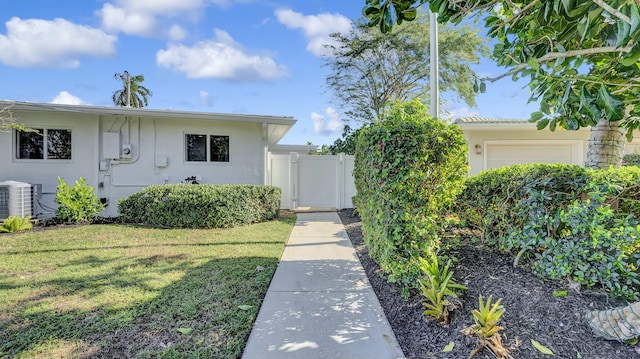 view of front of property featuring a front lawn, a garage, and central AC