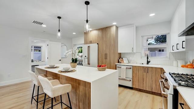 kitchen featuring a center island, sink, backsplash, high quality appliances, and white cabinets