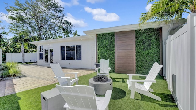 rear view of house featuring a lawn, a patio, and an outdoor fire pit