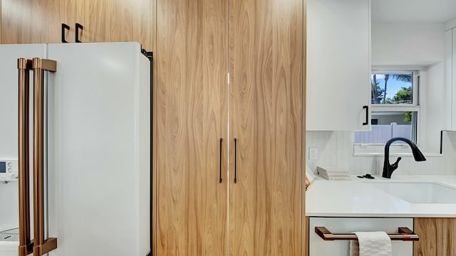 kitchen featuring dishwashing machine, backsplash, white fridge, and sink