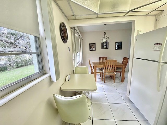 dining room featuring a paneled ceiling, a chandelier, light tile patterned floors, and a healthy amount of sunlight