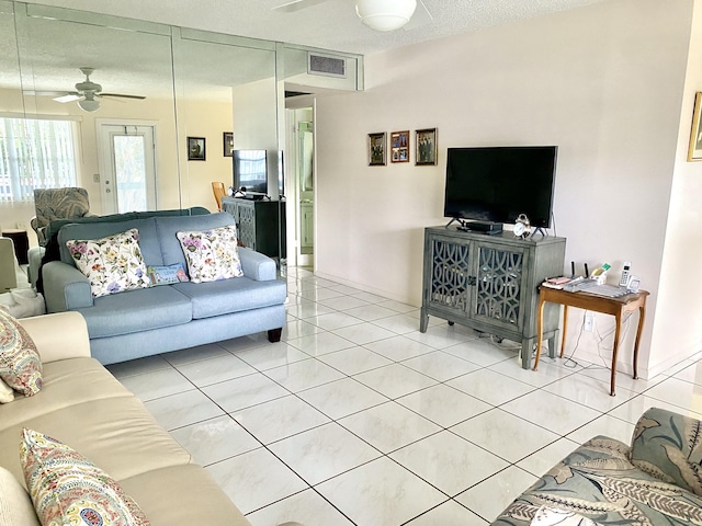 tiled living room with ceiling fan and a textured ceiling