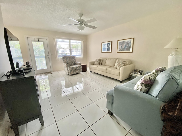 living room with ceiling fan, light tile patterned floors, and a textured ceiling