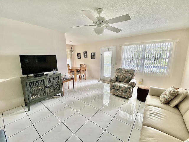 tiled living room with ceiling fan and a textured ceiling