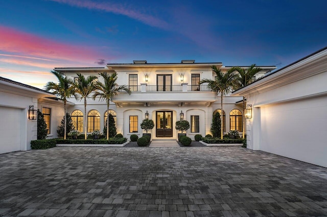 view of front of home with french doors, a balcony, and a garage