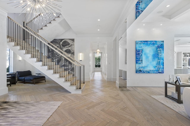 entryway with an inviting chandelier, crown molding, and light parquet floors