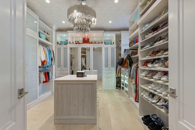 walk in closet featuring light wood-type flooring and a notable chandelier