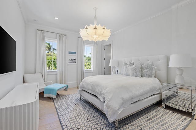 bedroom featuring an inviting chandelier, ornamental molding, and light hardwood / wood-style flooring