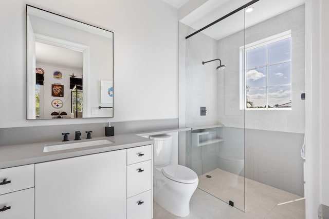 bathroom with a tile shower, vanity, and toilet