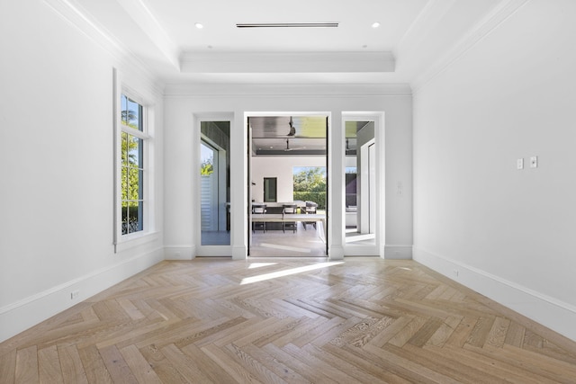 unfurnished room with a raised ceiling, light parquet floors, and crown molding