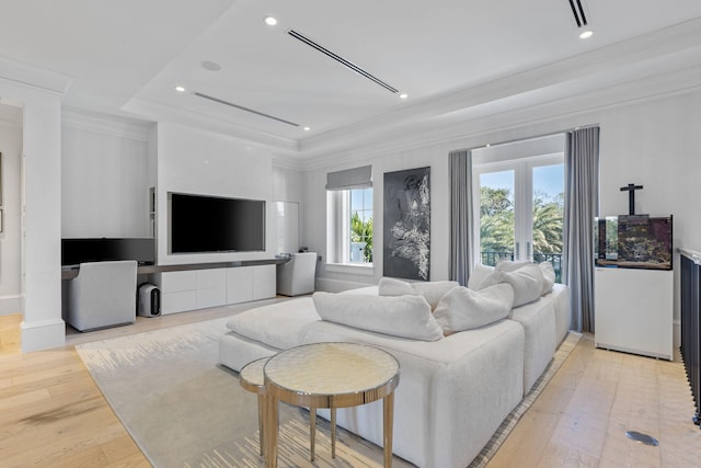 living room with a tray ceiling, light hardwood / wood-style floors, and ornamental molding