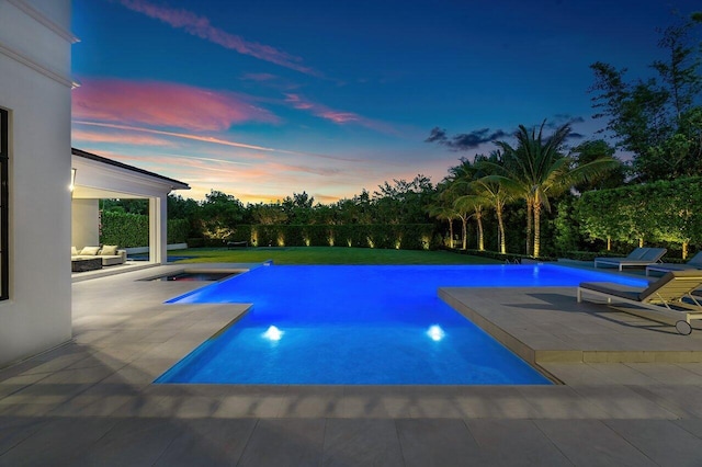 pool at dusk with a patio area and a jacuzzi