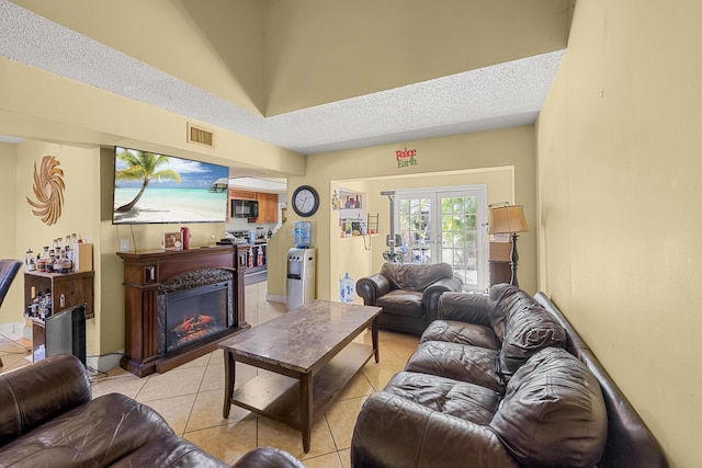 living room with french doors, light tile patterned flooring, and a textured ceiling