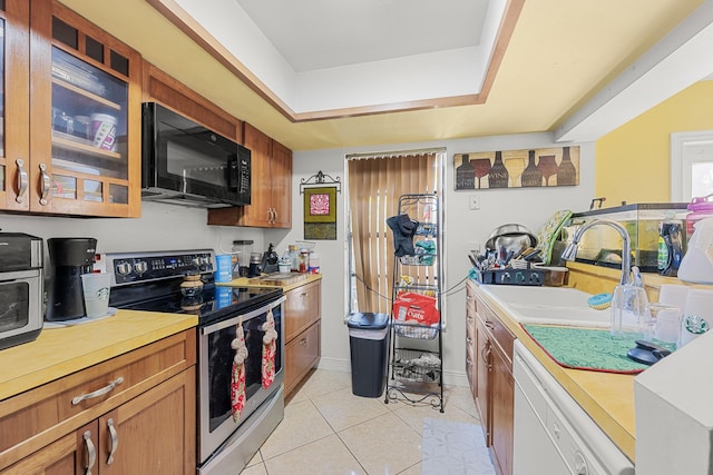 kitchen with white dishwasher, electric stove, sink, and light tile patterned floors