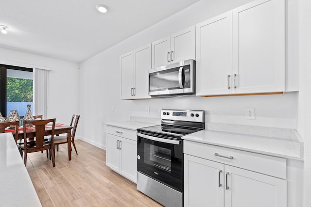 kitchen with light hardwood / wood-style floors, white cabinetry, and appliances with stainless steel finishes