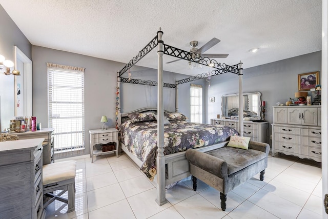 bedroom with ceiling fan, light tile patterned floors, and a textured ceiling