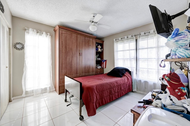 tiled bedroom featuring ceiling fan, a closet, a textured ceiling, and multiple windows