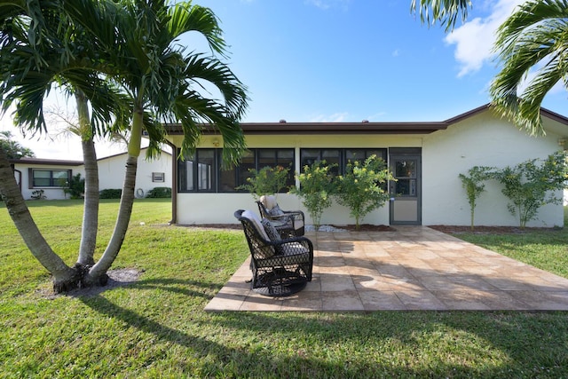 back of property with a lawn, a sunroom, and a patio area