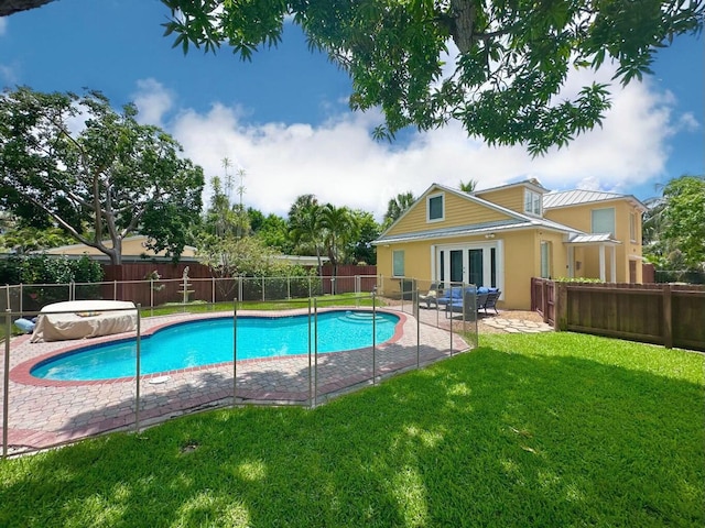 view of swimming pool featuring a lawn, a patio area, and french doors