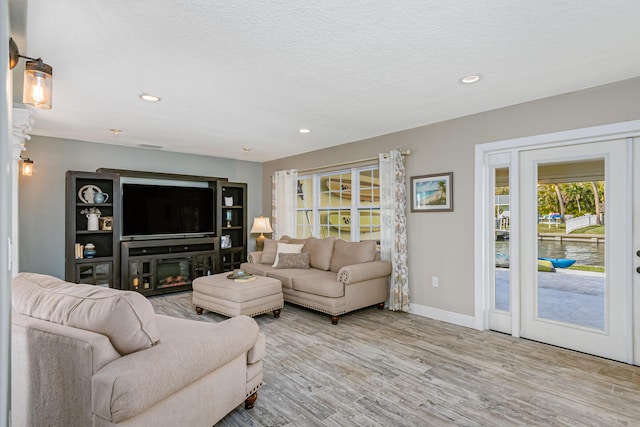 living room featuring light wood-type flooring and a textured ceiling