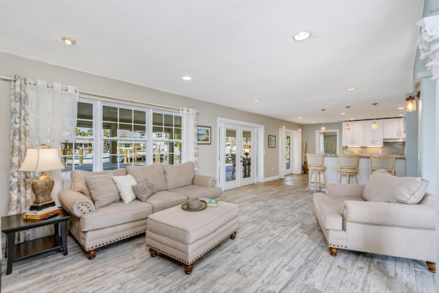 living room featuring french doors, a textured ceiling, and light hardwood / wood-style floors