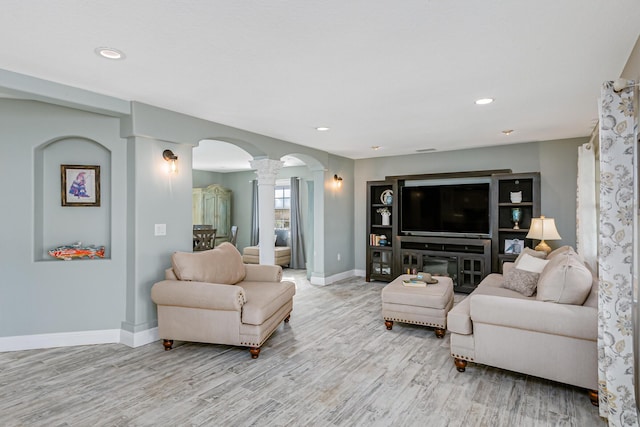 living room with light wood-type flooring and ornate columns