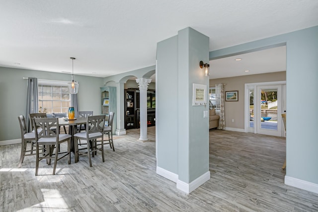 dining area with ornate columns and light hardwood / wood-style floors