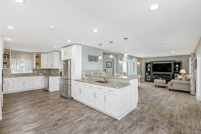 kitchen with white cabinetry, stainless steel appliances, hanging light fixtures, and sink