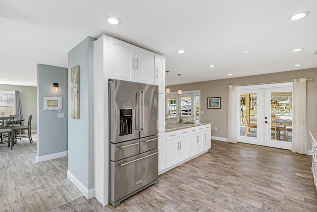 kitchen with pendant lighting, white cabinets, french doors, light stone counters, and high end refrigerator