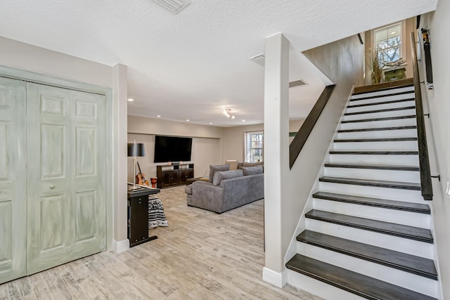 stairs with a textured ceiling and hardwood / wood-style flooring