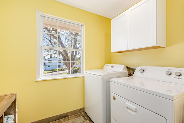 clothes washing area featuring cabinets, a wealth of natural light, and washer and clothes dryer