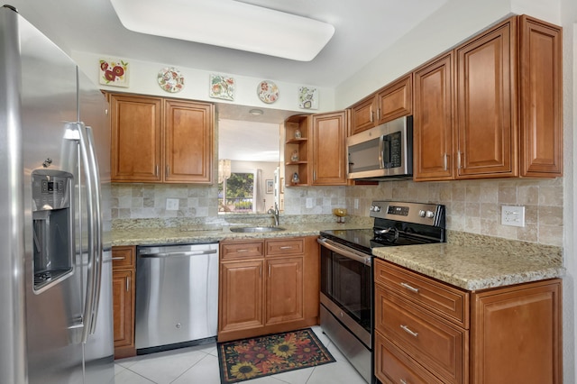 kitchen featuring sink, tasteful backsplash, light tile patterned flooring, light stone counters, and stainless steel appliances