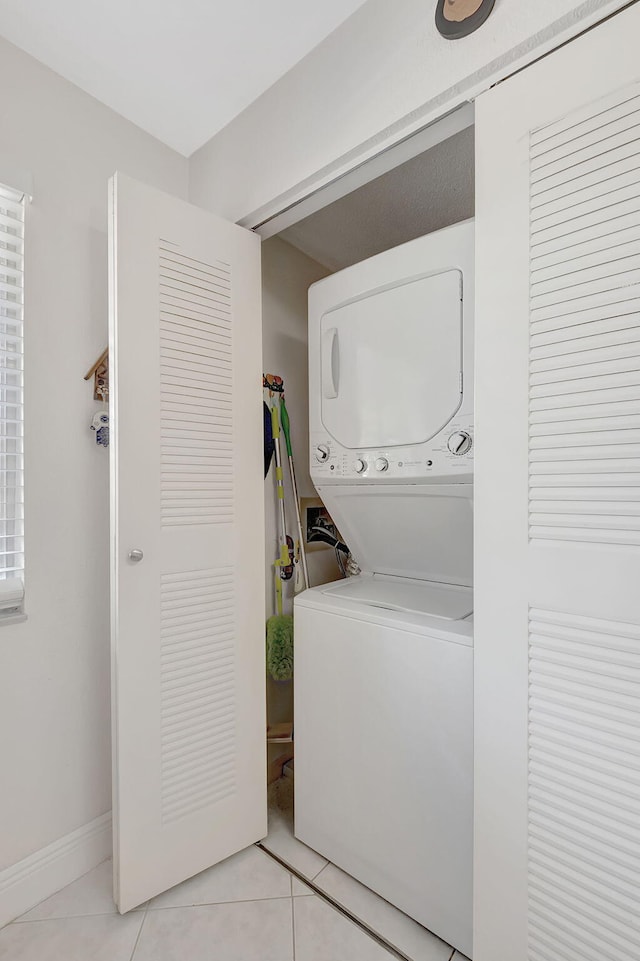 laundry area featuring light tile patterned floors and stacked washer and dryer