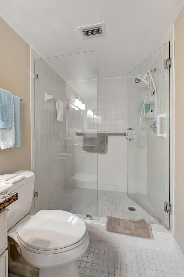 bathroom featuring tile patterned flooring, toilet, and a shower with shower door