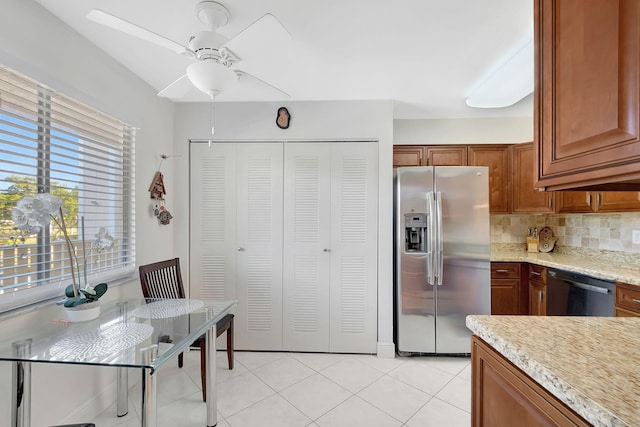 kitchen with backsplash, ceiling fan, light stone countertops, light tile patterned flooring, and stainless steel appliances