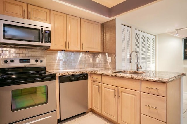 kitchen featuring appliances with stainless steel finishes, sink, light stone countertops, and decorative backsplash